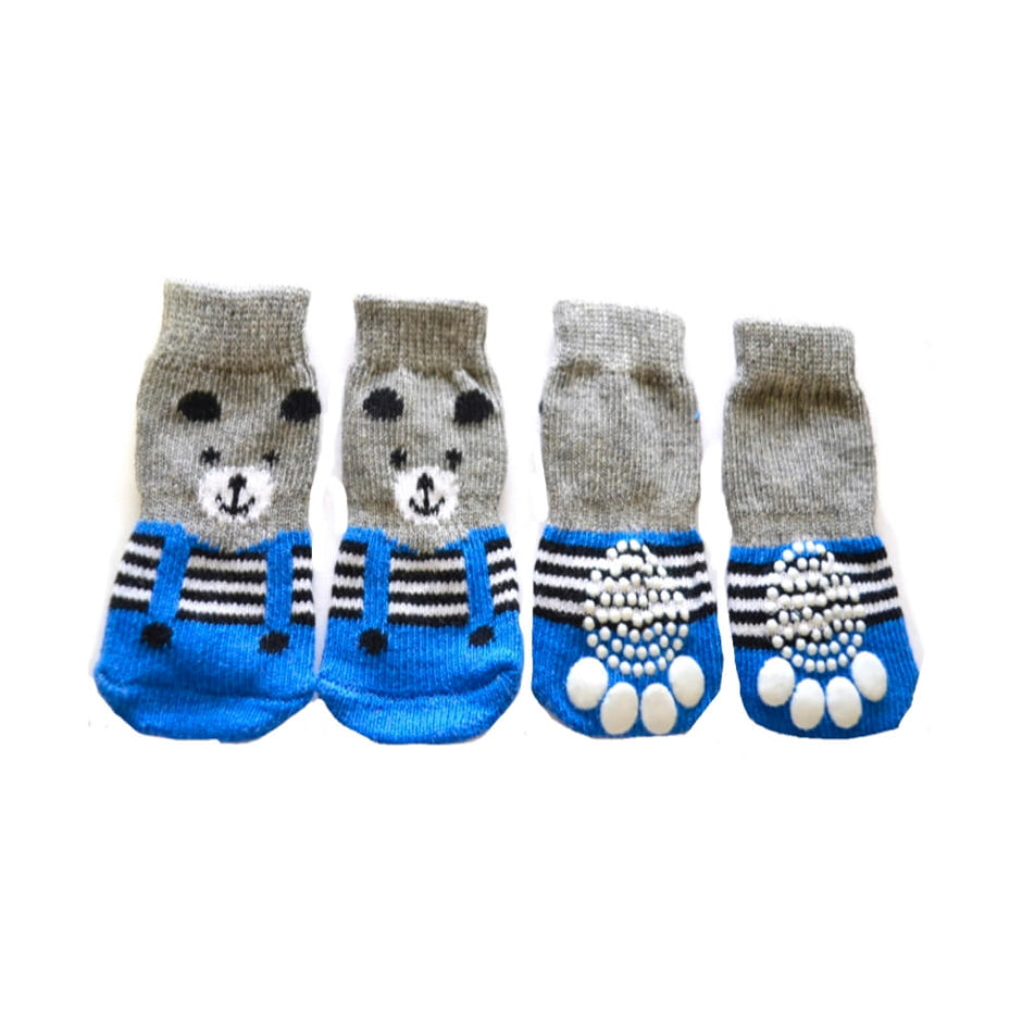 Four pairs of dog socks with cartoon faces and blue soles on a white background