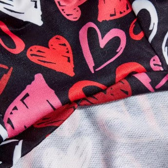 Close-up of fabric with red, pink, and white hearts on a black background