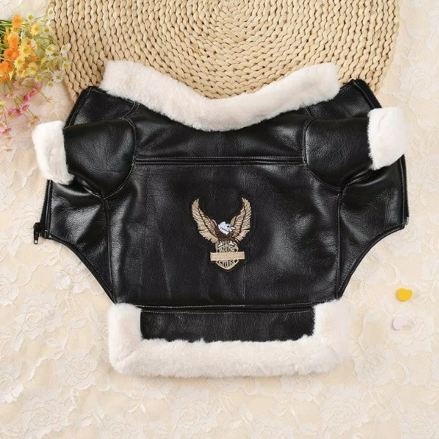 Black leather dog coat with white fur lining and embroidered eagle design on a textured beige background.