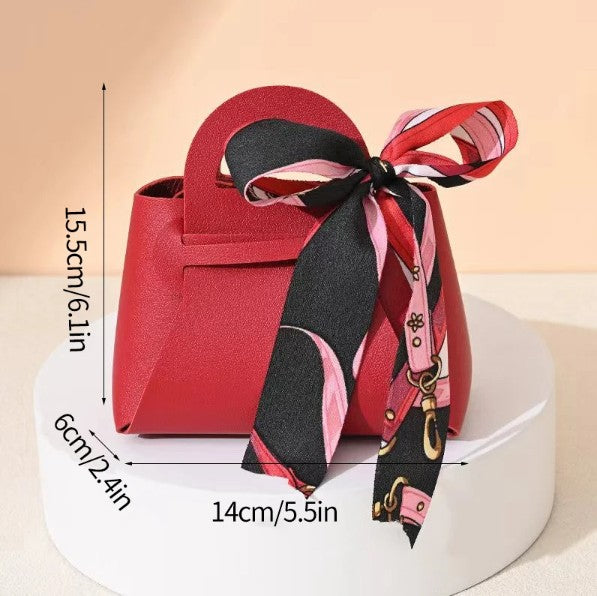 Red handbag with a decorative scarf and measurements on a beige background