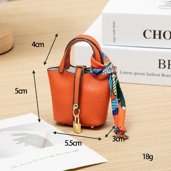 Orange handbag with a decorative scarf, shown with measurements on a wooden surface.