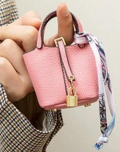 Pink handbag with a strap held by a person, on a neutral background