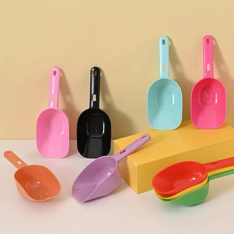 Set of colorful plastic scoops on a beige background