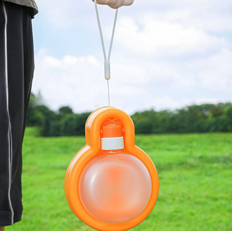Orange dog water bottle with a strap against a green outdoor background