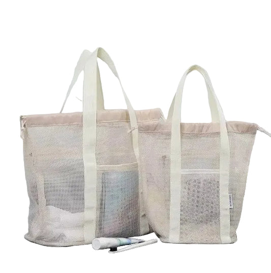 Two beige mesh laundry bags on a dark surface with a marble wall background.